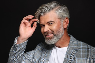 Portrait of smiling man with beautiful hairstyle on black background