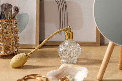 Mirror, jewelry and perfume on wooden dressing table