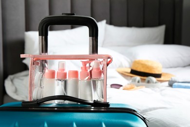 Photo of Cosmetic travel kit. Plastic bag with small containers of personal care products on suitcase in bedroom, space for text