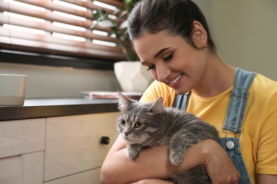 Young woman with cute cat at home, space for text. Pet and owner