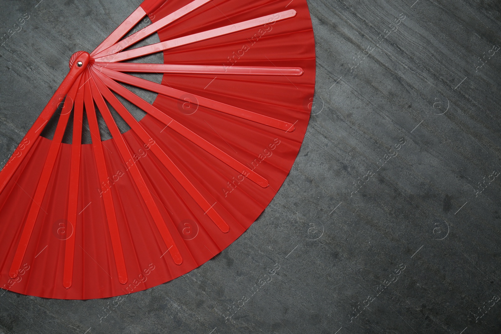 Photo of Bright red hand fan on grey background, top view. Space for text