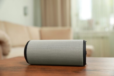 Photo of Portable bluetooth speaker on wooden table indoors. Audio equipment