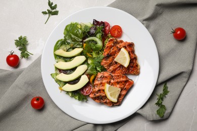 Tasty grilled salmon with avocado, lemon and tomatoes on light grey table, flat lay