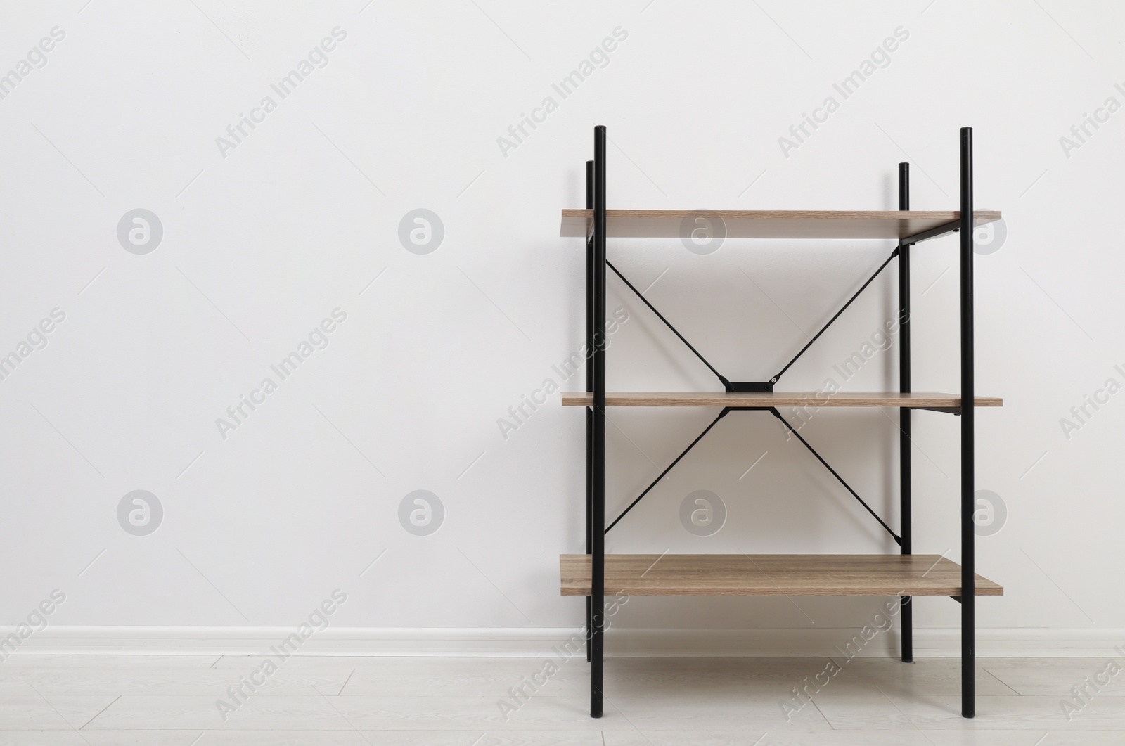 Photo of Modern wooden shelves unit at light wall. Space for text