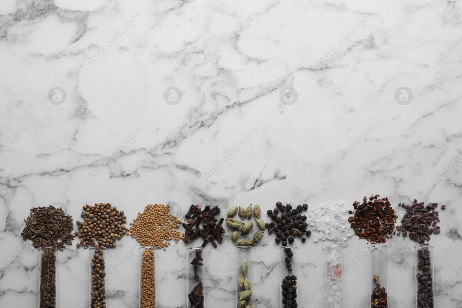 Photo of Glass tubes with different spices on white marble table, flat lay. Space for text