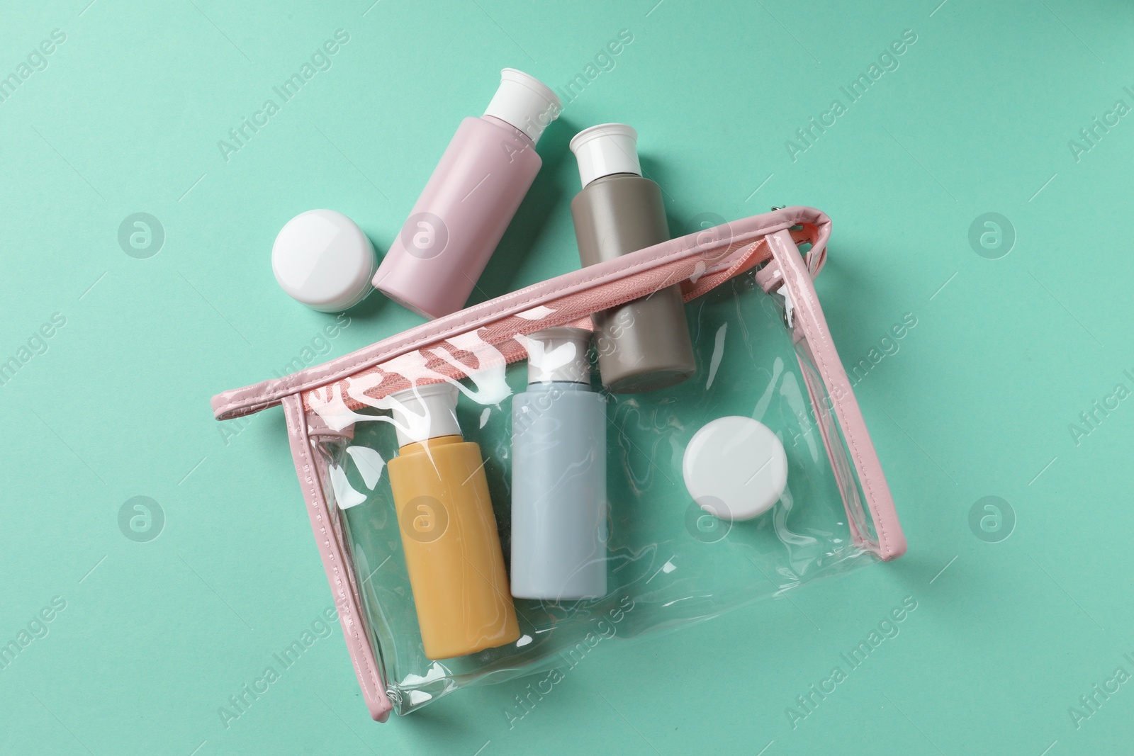 Photo of Plastic bag with cosmetic travel kit on turquoise background, flat lay. Bath accessories