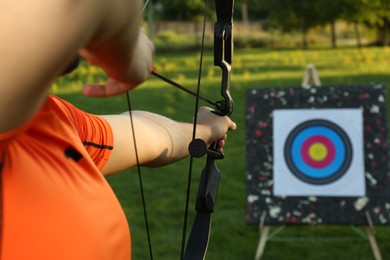 Photo of Man with bow and arrow aiming at archery target in park, closeup
