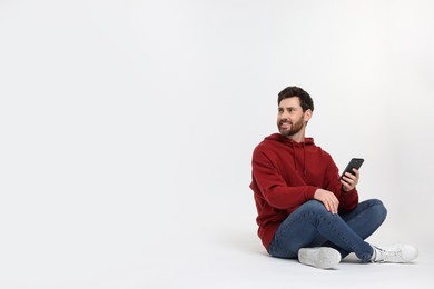 Happy man with smartphone on white background. Space for text