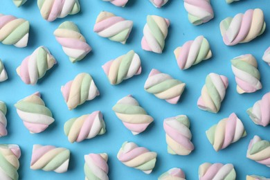 Delicious colorful marshmallows on light blue background, flat lay