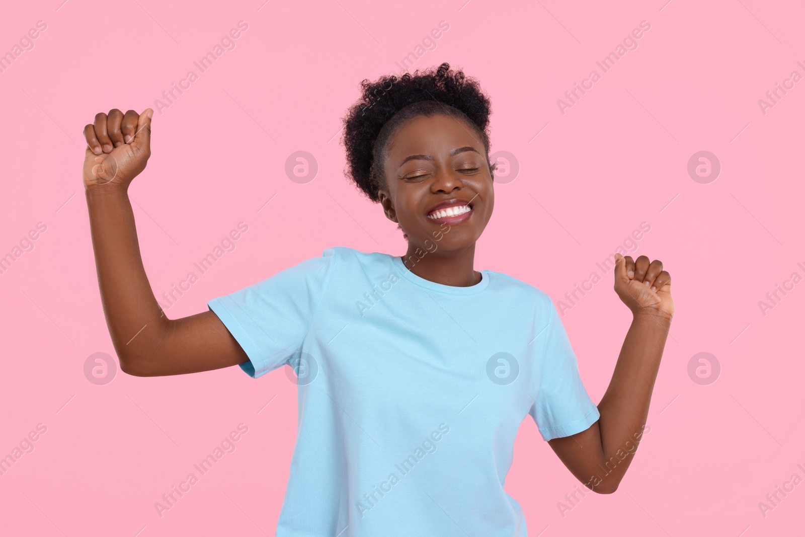 Photo of Happy young woman dancing on pink background