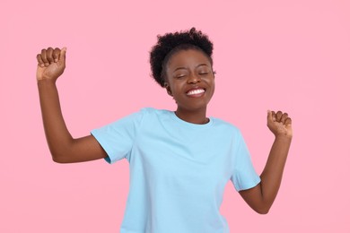 Photo of Happy young woman dancing on pink background