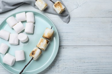 Fresh and roasted marshmallows on white wooden table, flat lay. Space for text