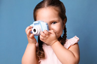 Photo of Little photographer taking picture with toy camera on blue background