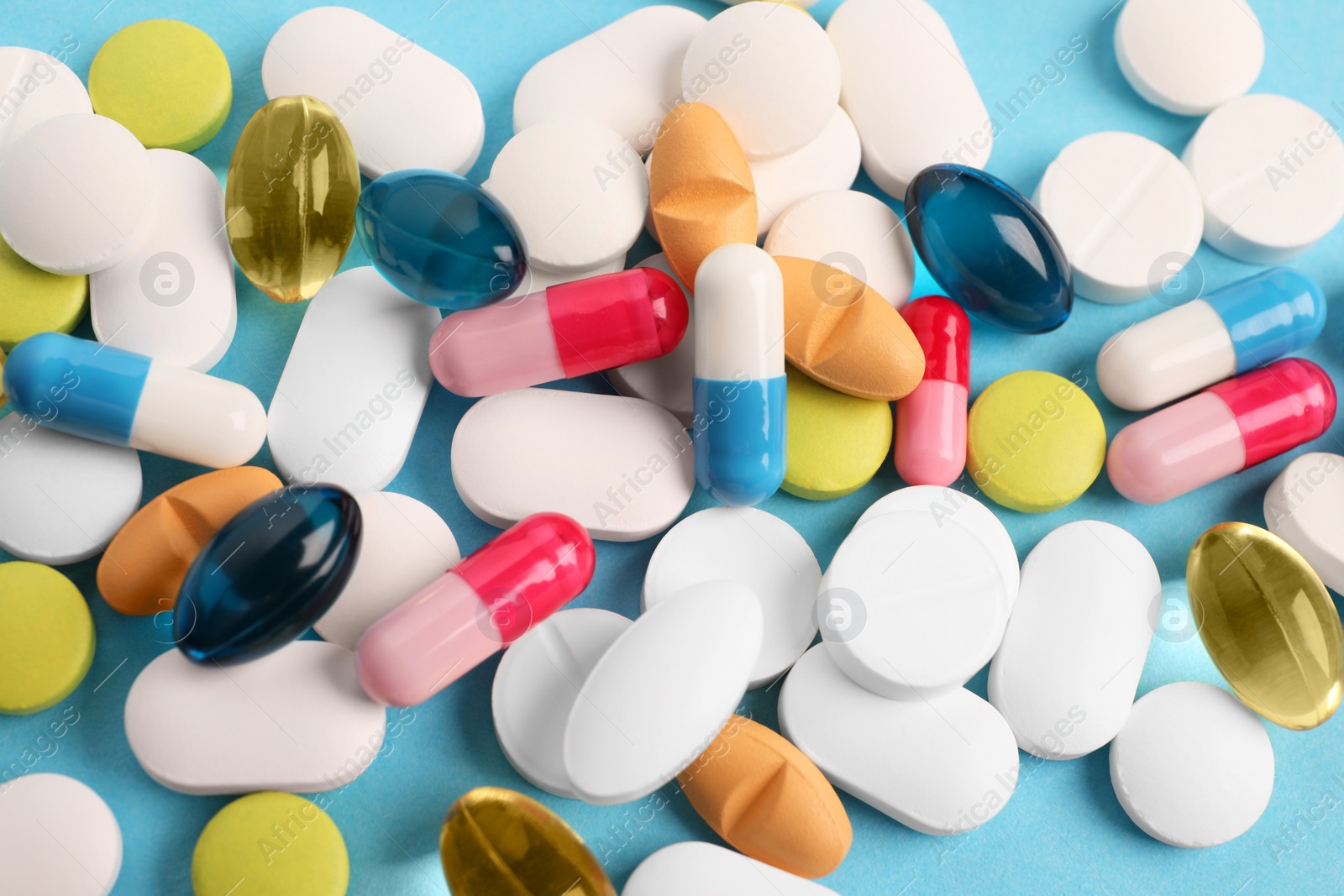 Photo of Pile of different pills on light blue background, flat lay