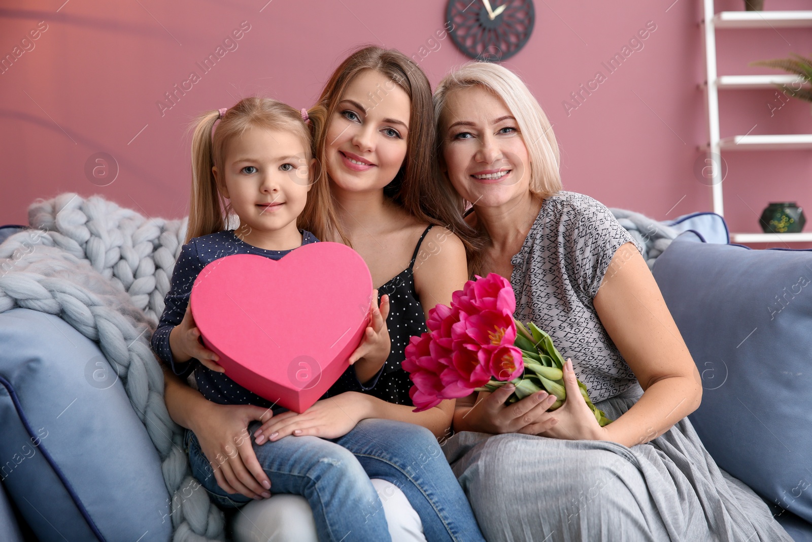 Photo of Happy young woman with her mother and daughter at home