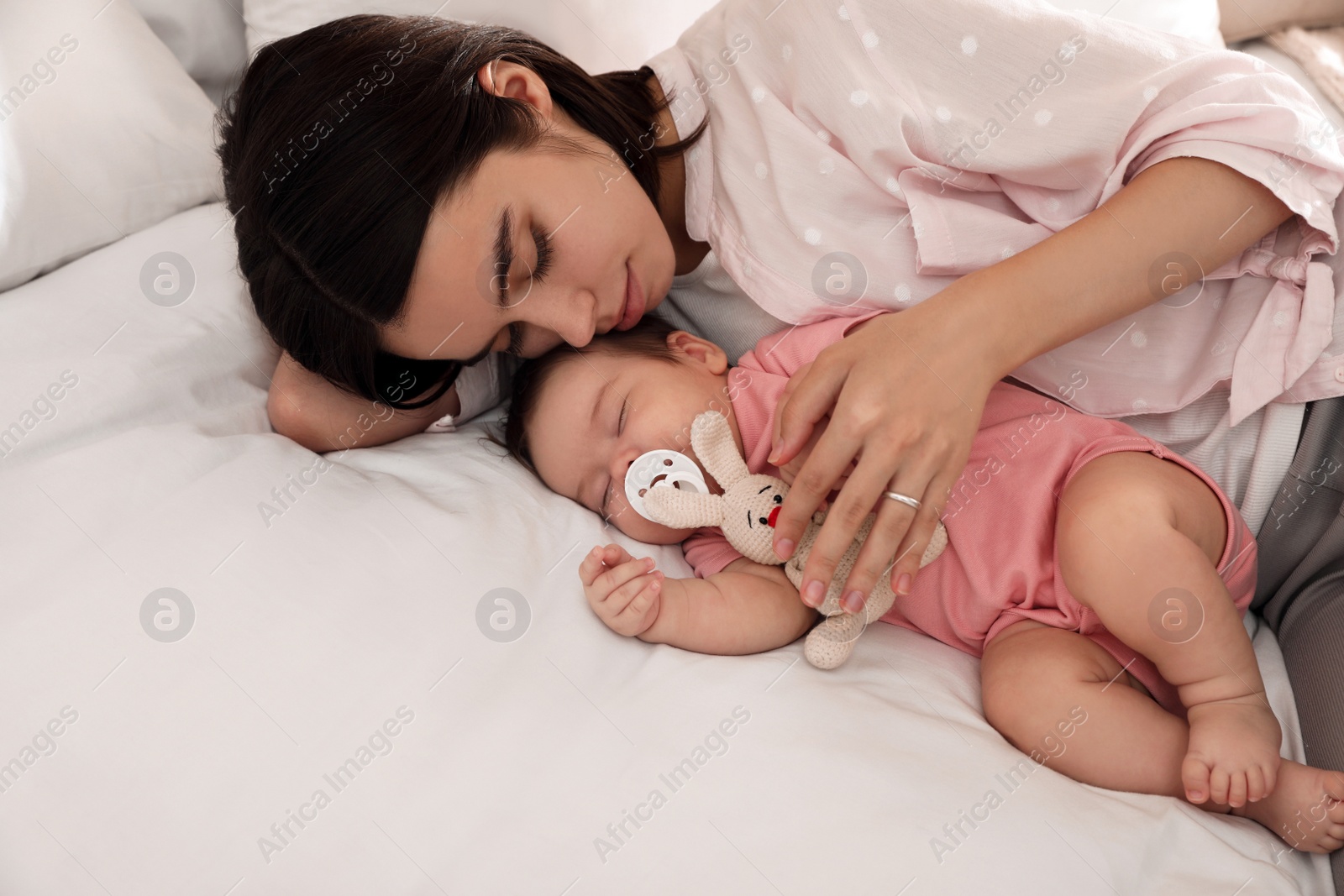 Photo of Young mother resting near her sleeping baby on bed. Space for text