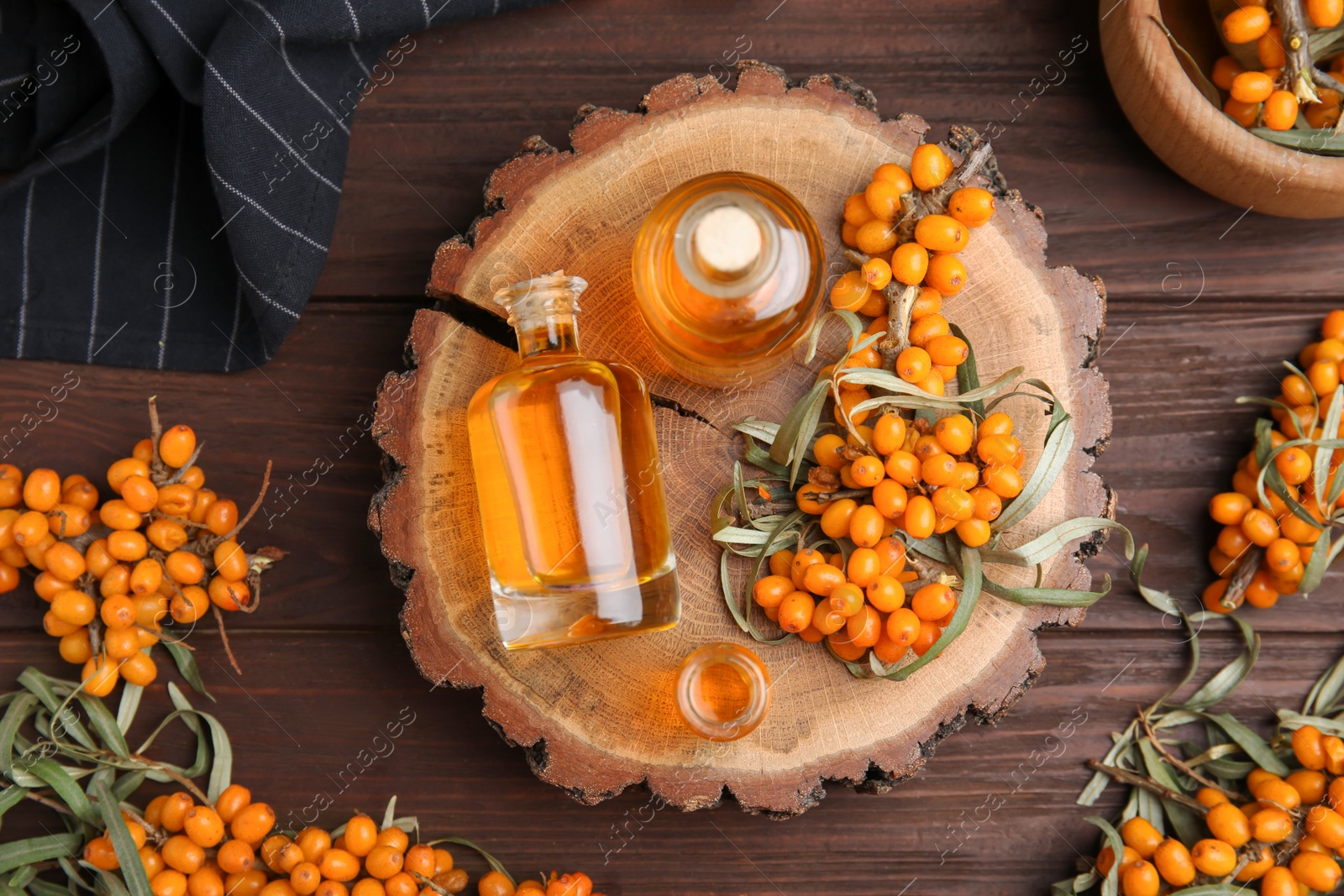 Photo of Natural sea buckthorn oil and fresh berries on wooden table, flat lay