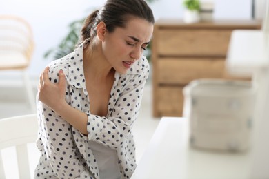 Woman suffering from shoulder pain in office. Bad posture problem