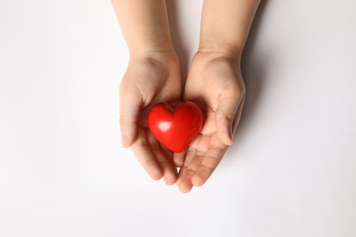 Photo of Woman holding red heart in hands on white background, top view