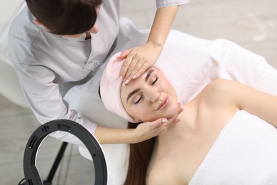 Photo of Cosmetologist making face massage to client in clinic, top view