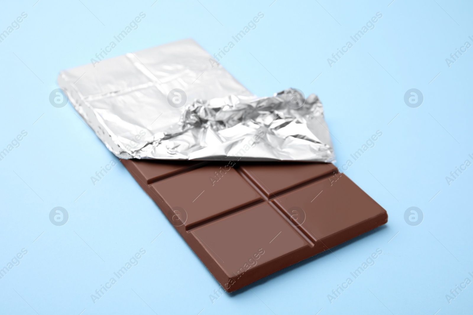 Photo of One tasty chocolate bar on light blue background