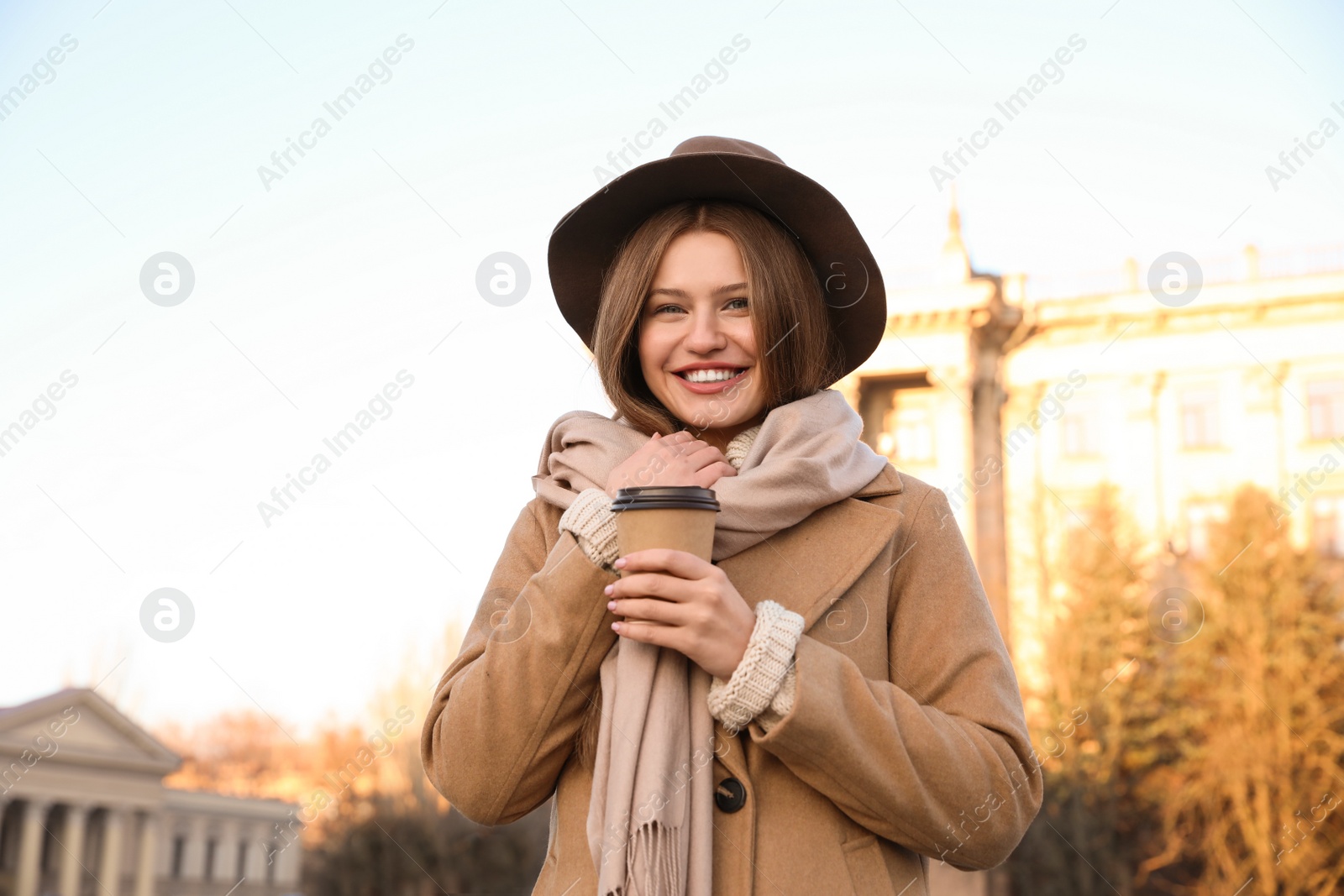 Photo of Young woman with cup of coffee on city street in morning