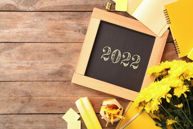 Image of Back to school 2022. Blackboard, stationery and flowers on wooden table, flat lay