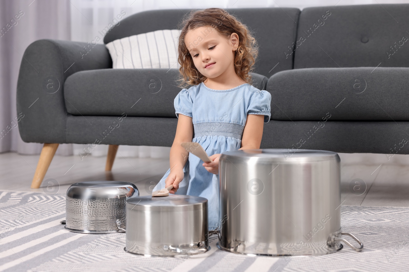 Photo of Little girl pretending to play drums on pots at home