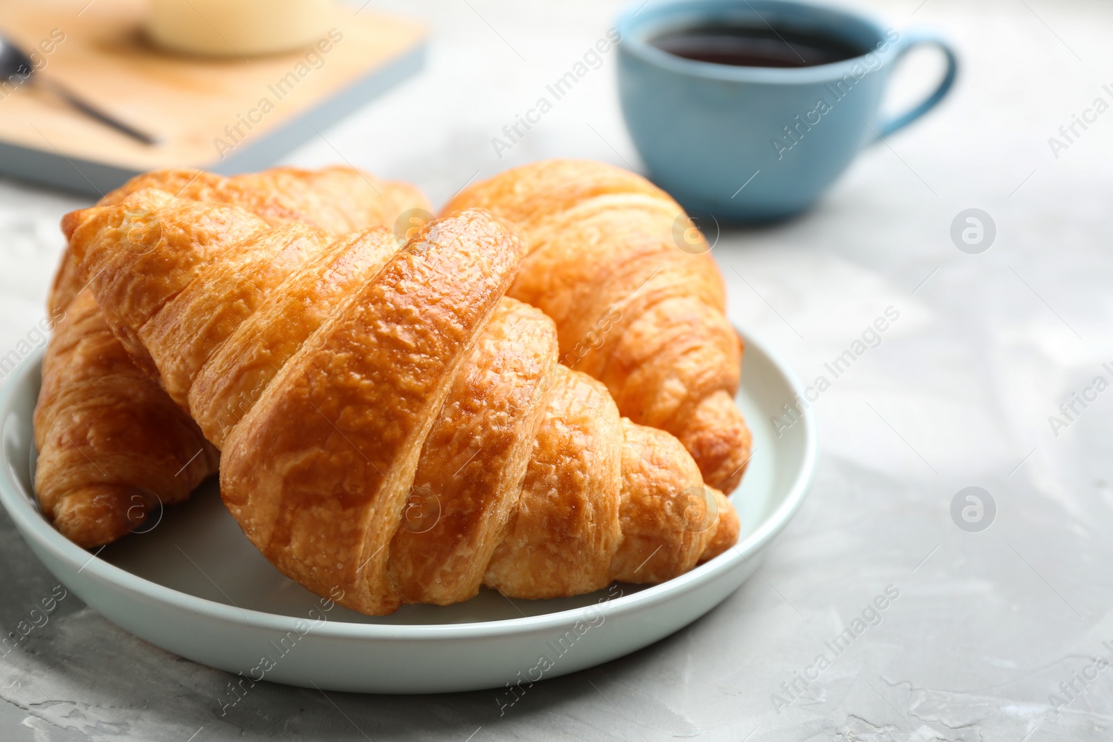 Photo of Plate of fresh croissants on grey table, closeup. French pastry