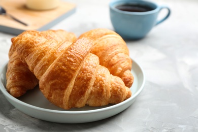 Plate of fresh croissants on grey table, closeup. French pastry