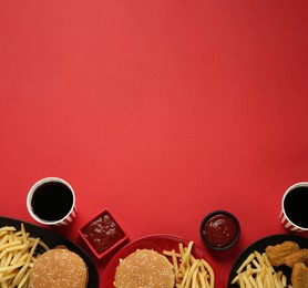 Photo of Different fast food on red background, flat lay. Space for text