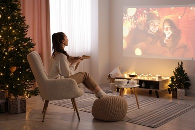 Photo of Woman with pizza watching romantic Christmas movie via video projector at home