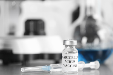 Photo of Chickenpox vaccine and syringe on table in laboratory, space for text. Varicella virus prevention