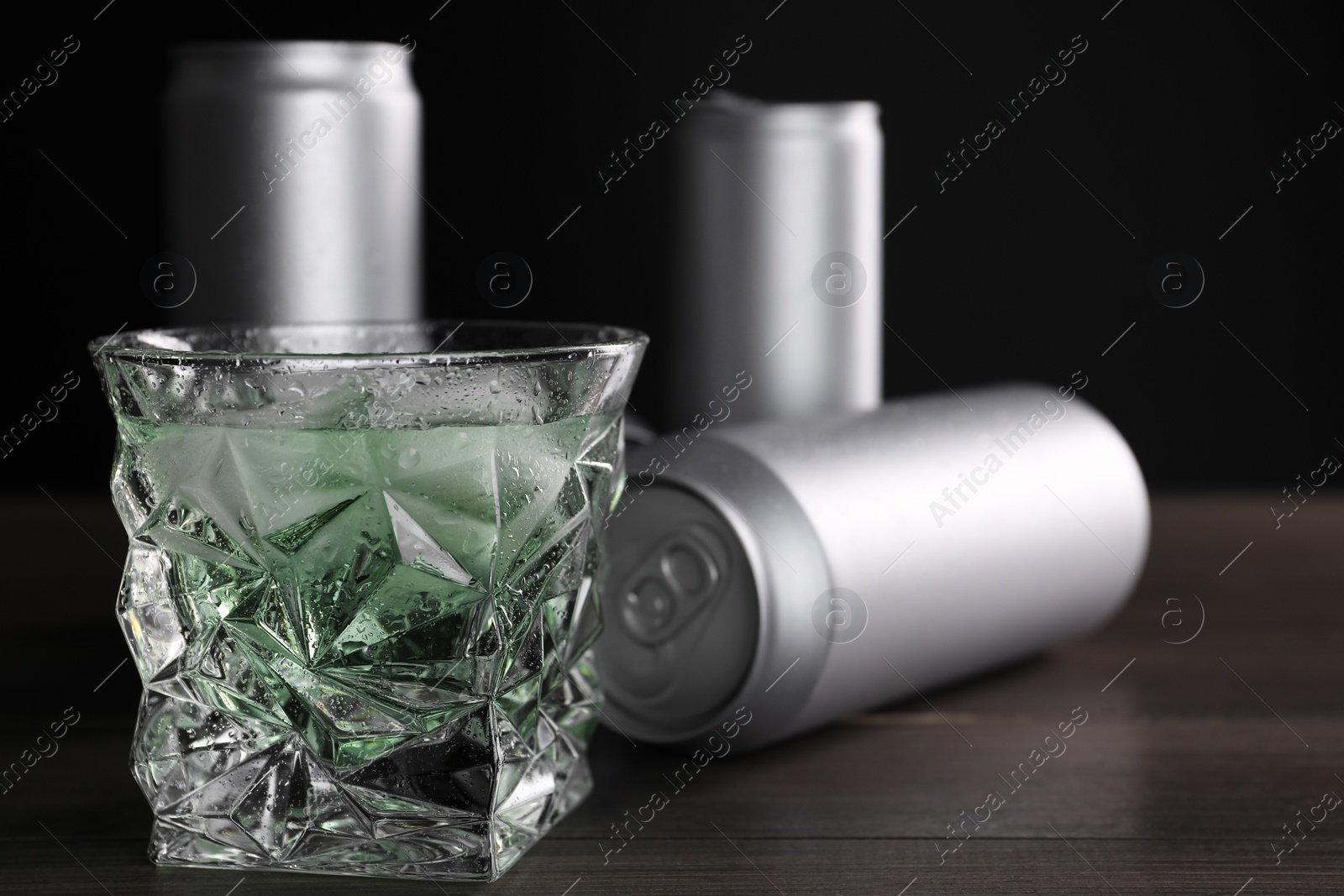 Photo of Energy drink in glass and aluminium cans on wooden table, closeup. Space for text