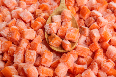 Photo of Frozen carrots and wooden spoon, closeup. Vegetable preservation