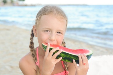 Photo of Cute little girl eating juicy watermelon on beach