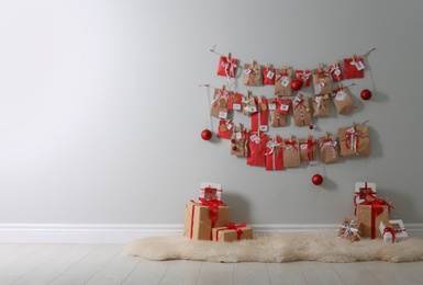 Christmas advent calendar hanging on wall above gift boxes, space for text