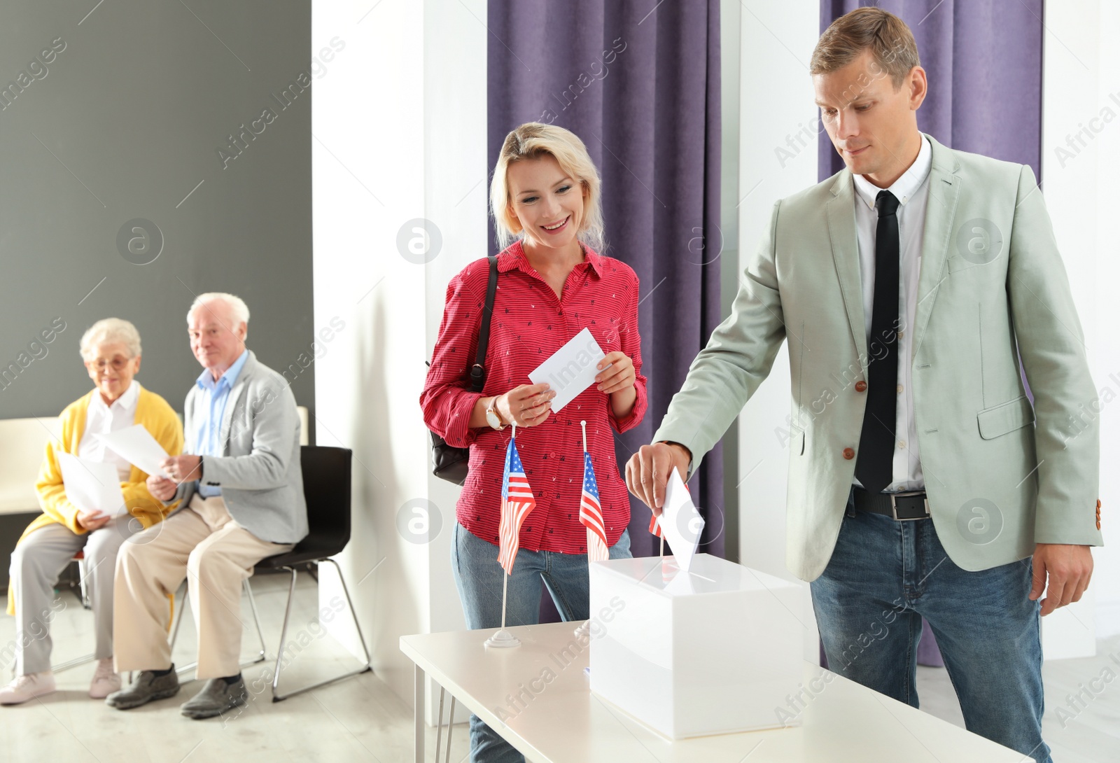 Photo of Man putting ballot paper into box at polling station