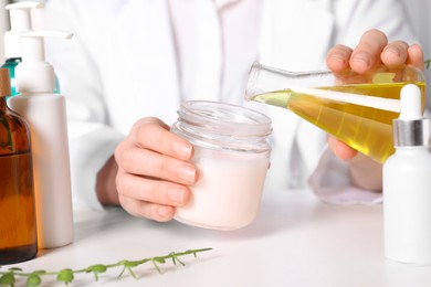 Photo of Dermatologist developing cosmetic product at white table indoors, selective focus