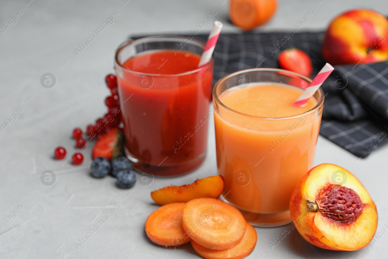 Photo of Delicious juices and fresh ingredients on grey table. Space for text