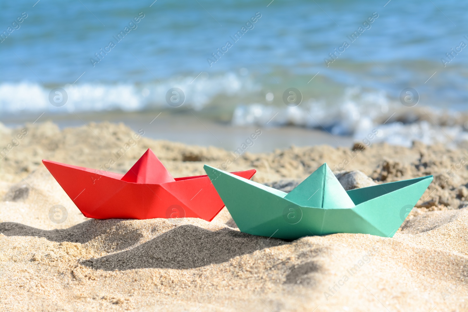 Photo of Two paper boats near sea on sunny day