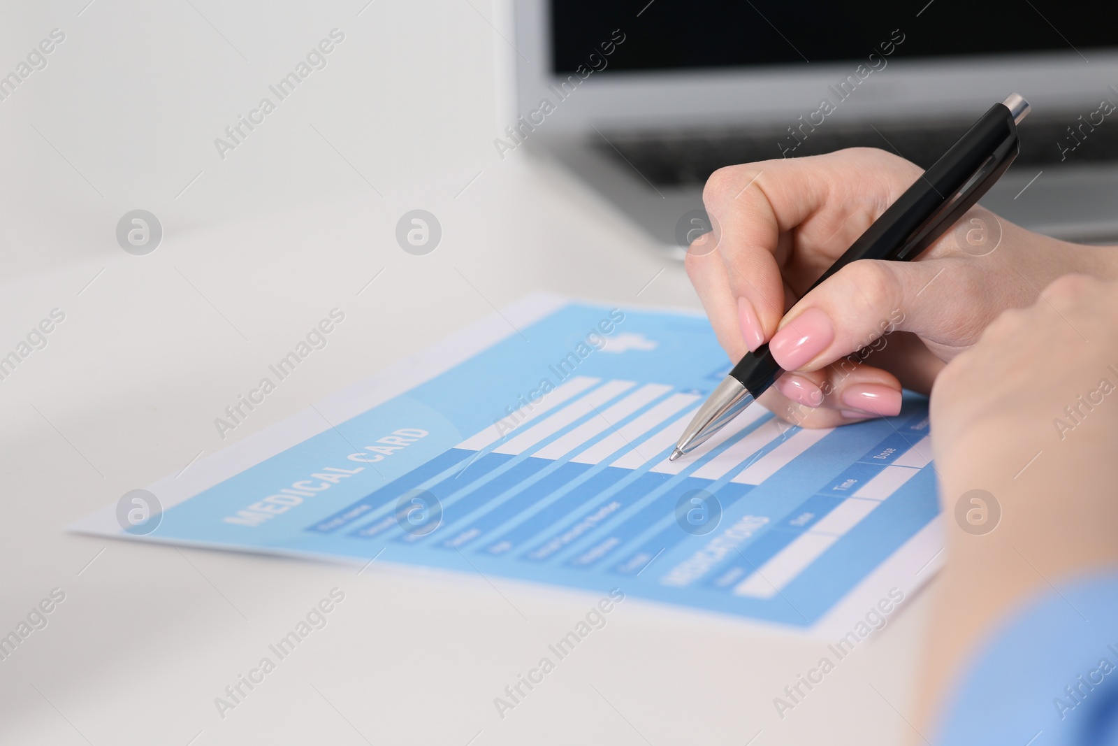 Photo of Doctor filling patient's medical card at table in clinic, closeup