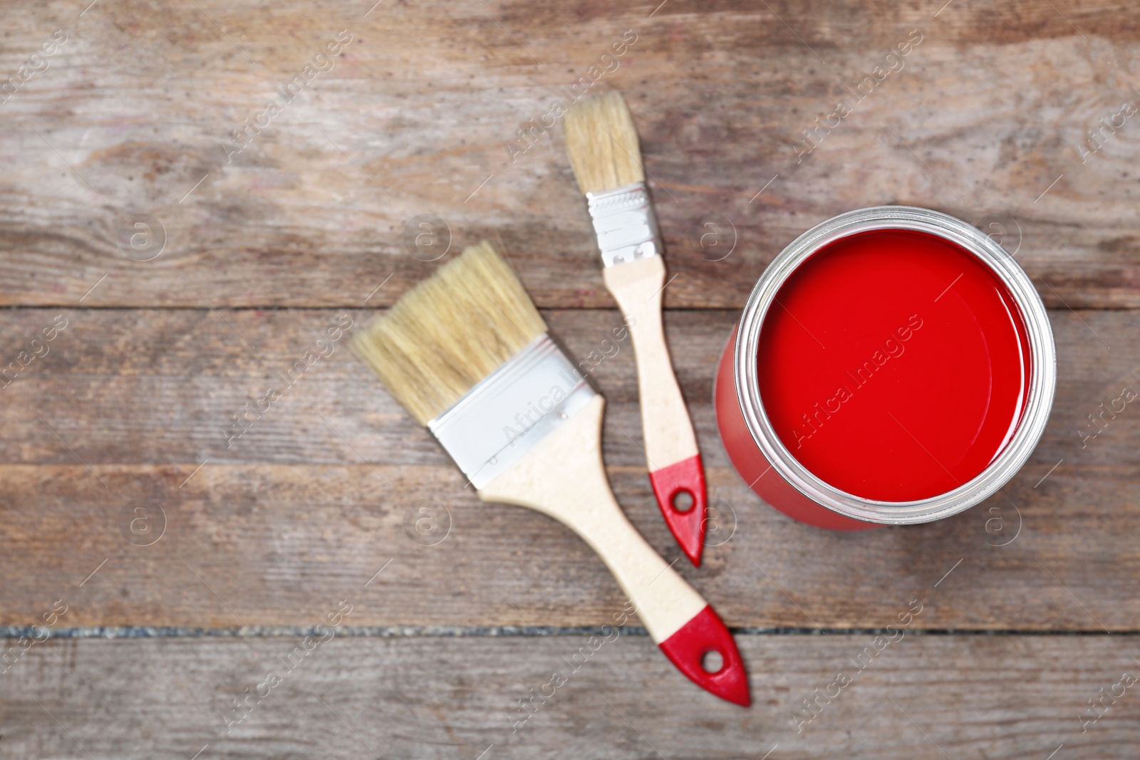 Photo of Tin can with paint and brushes on wooden background, top view