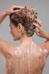 Photo of Woman washing hair on light grey background, back view