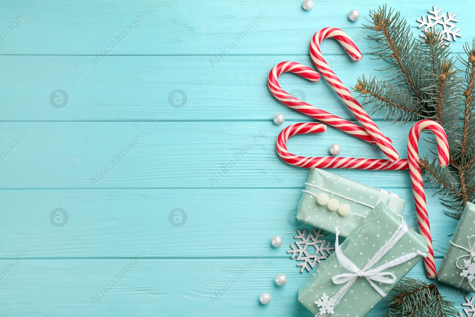 Photo of Flat lay composition with candy canes and Christmas decor on cyan wooden table. Space for text