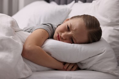 Photo of Little girl suffering from headache in bed