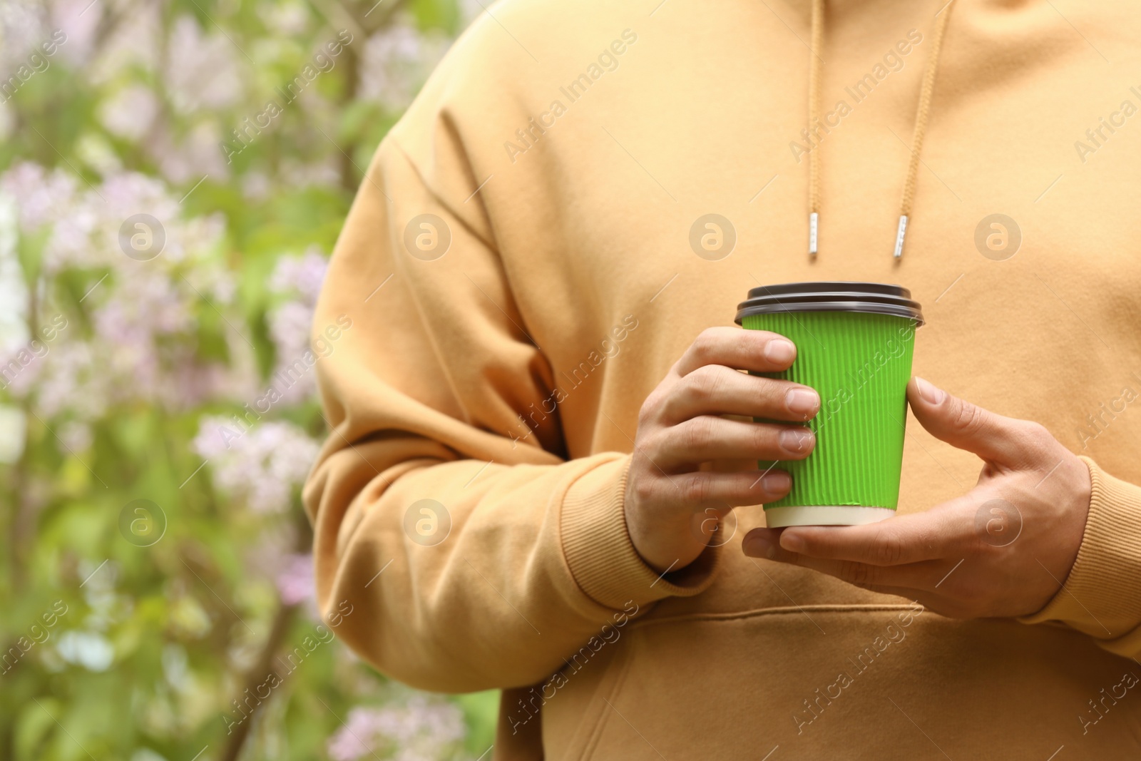 Photo of Man with takeaway coffee cup in park, closeup