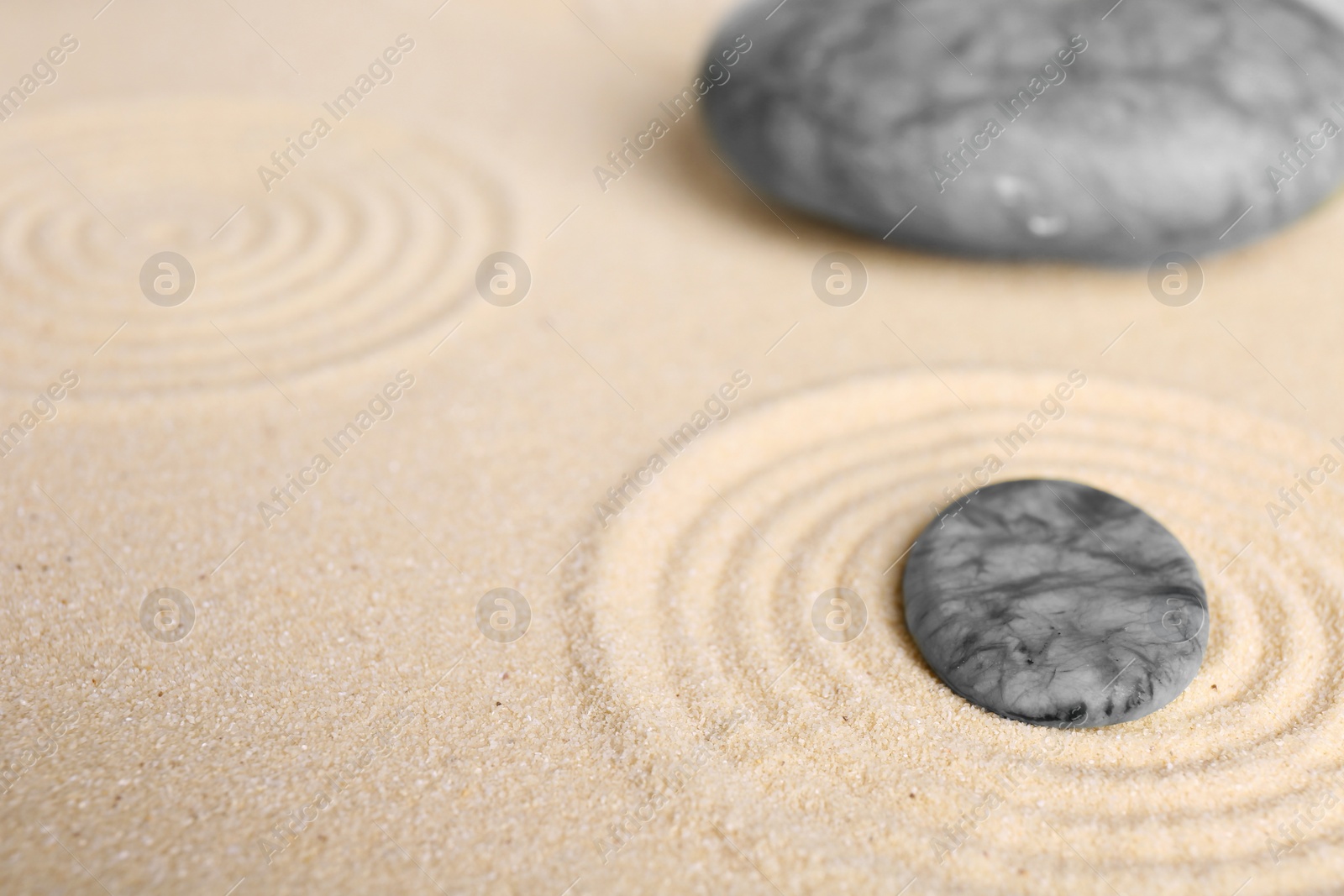 Photo of Zen garden stones on beige sand with pattern