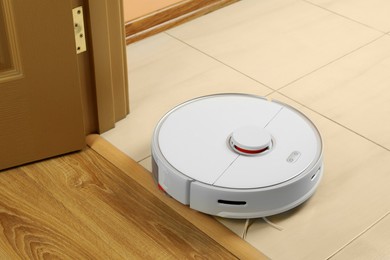 Photo of Modern robotic vacuum cleaner on white floor indoors