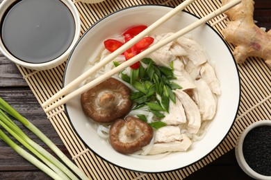 Photo of Delicious ramen with meat and ingredients on wooden table, flat lay. Noodle soup